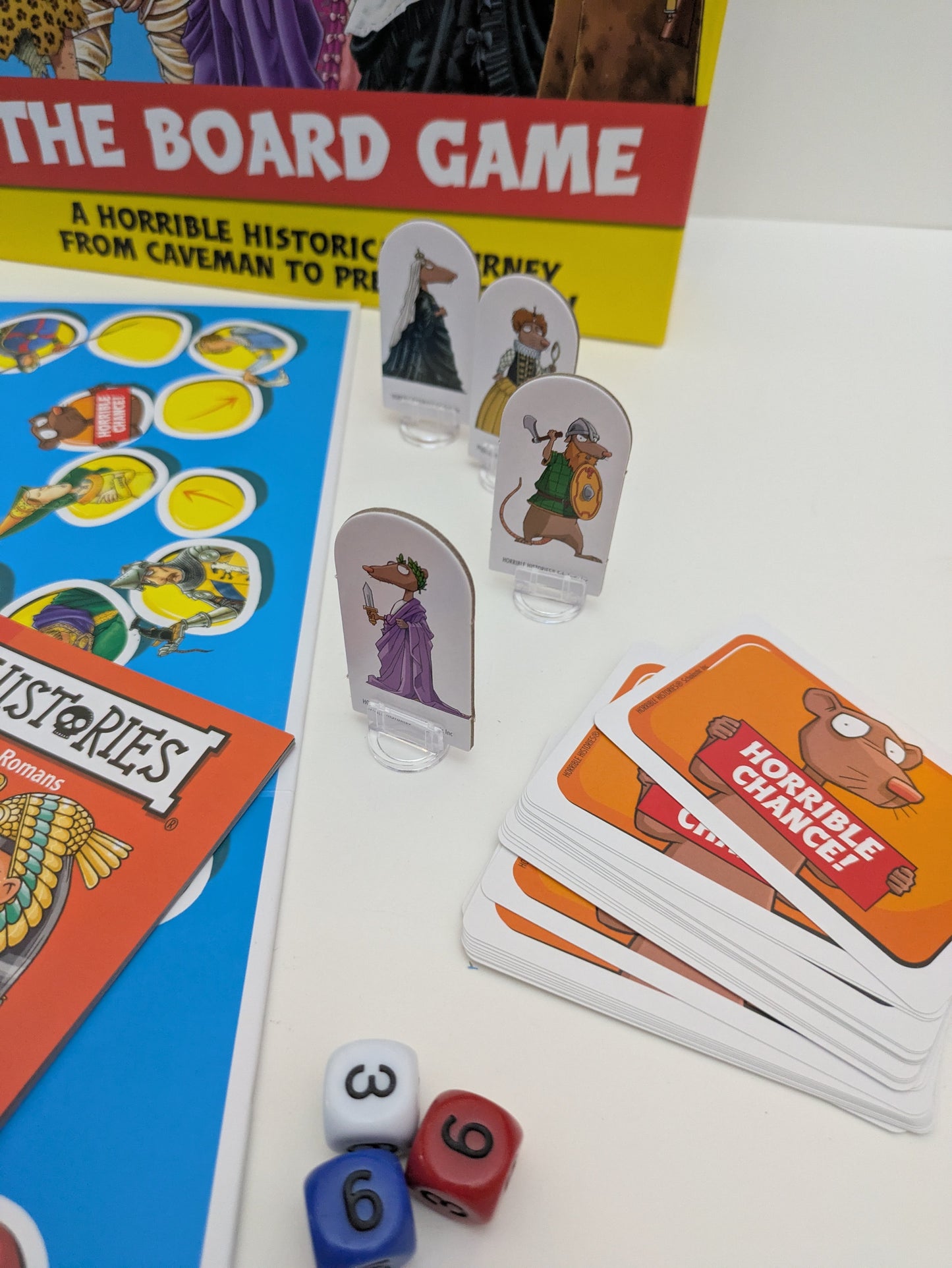 Complete setup of Horrible Histories: The Board Game, including the board, dice, question booklets, and player tokens.