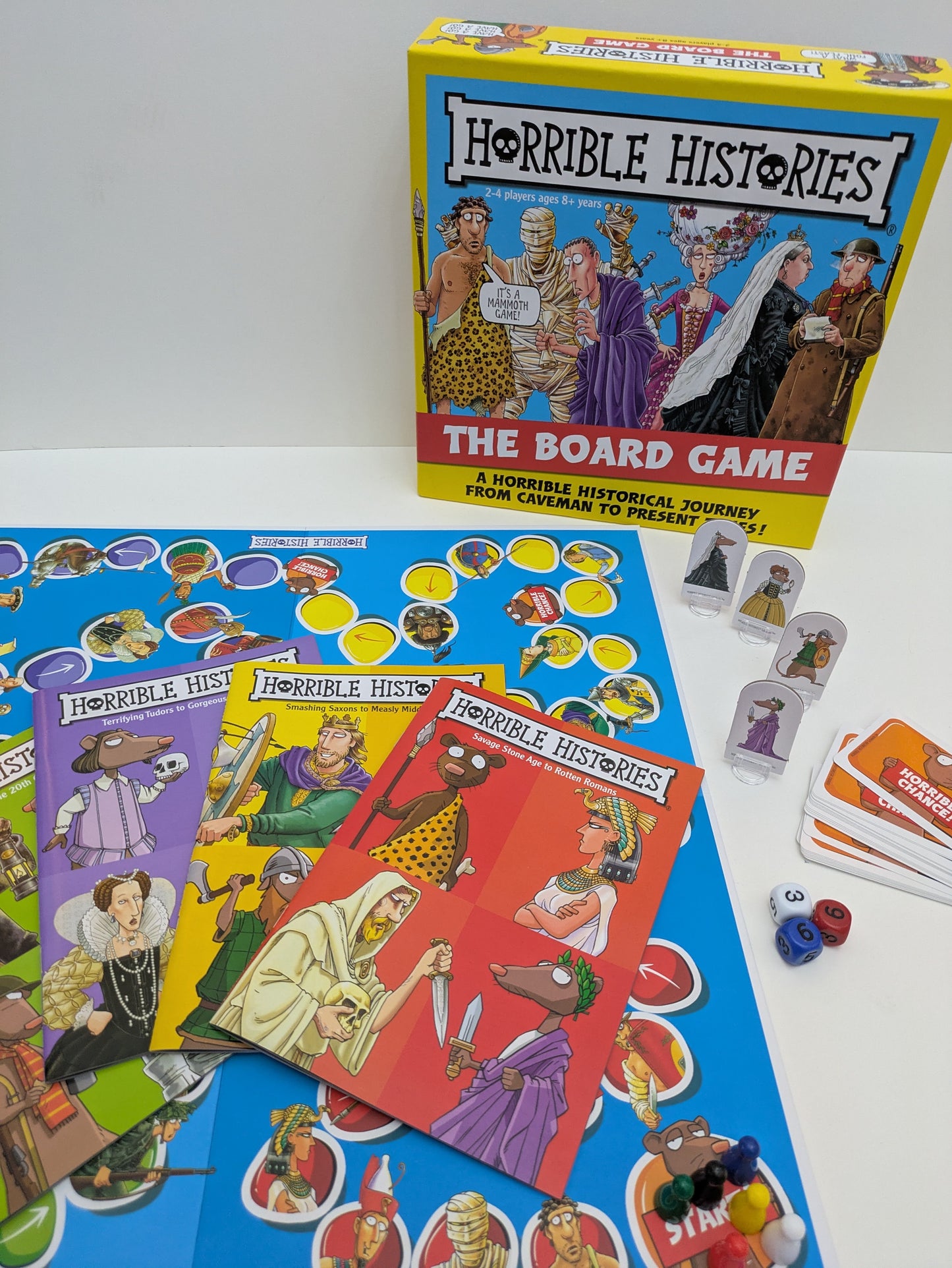 Complete setup of Horrible Histories: The Board Game, including the board, dice, question booklets, and player tokens.