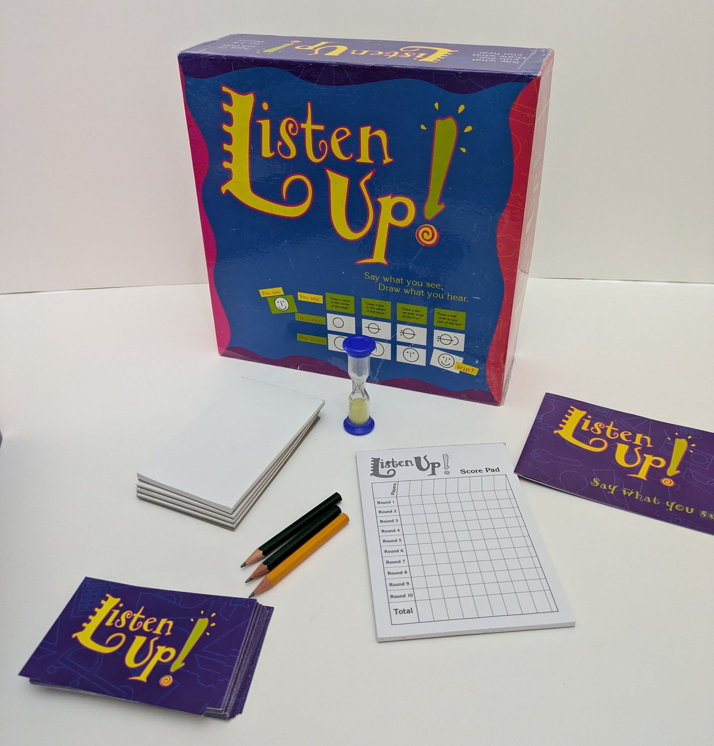 "Complete Listen Up (1997) game setup with geometric cards, drawing pads, and pencils ready for a fun-filled creative drawing and listening challenge."