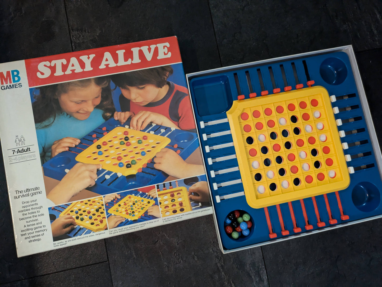 "Stay Alive (1975) game box featuring the marble survival board and sliding dials, emphasizing strategic and competitive gameplay."