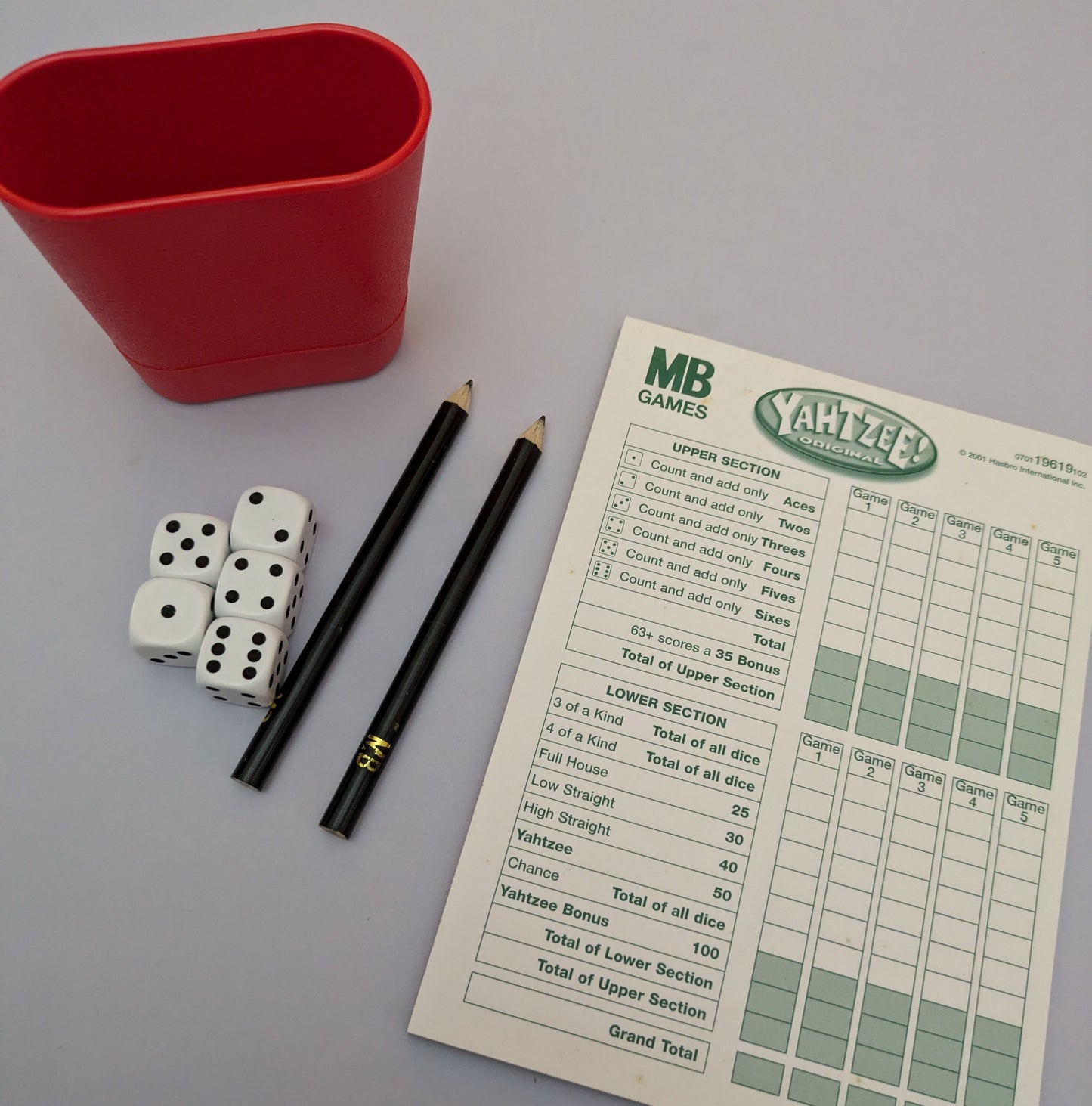 "Complete Yahtzee game setup with dice, scorecards, and a dice cup ready for exciting dice-rolling action."