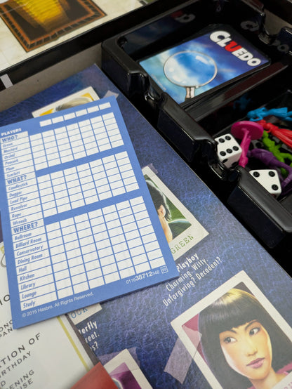 Complete setup of Cluedo (2012) with board, suspect cards, weapon tokens, and player pieces ready for a thrilling mystery game night.