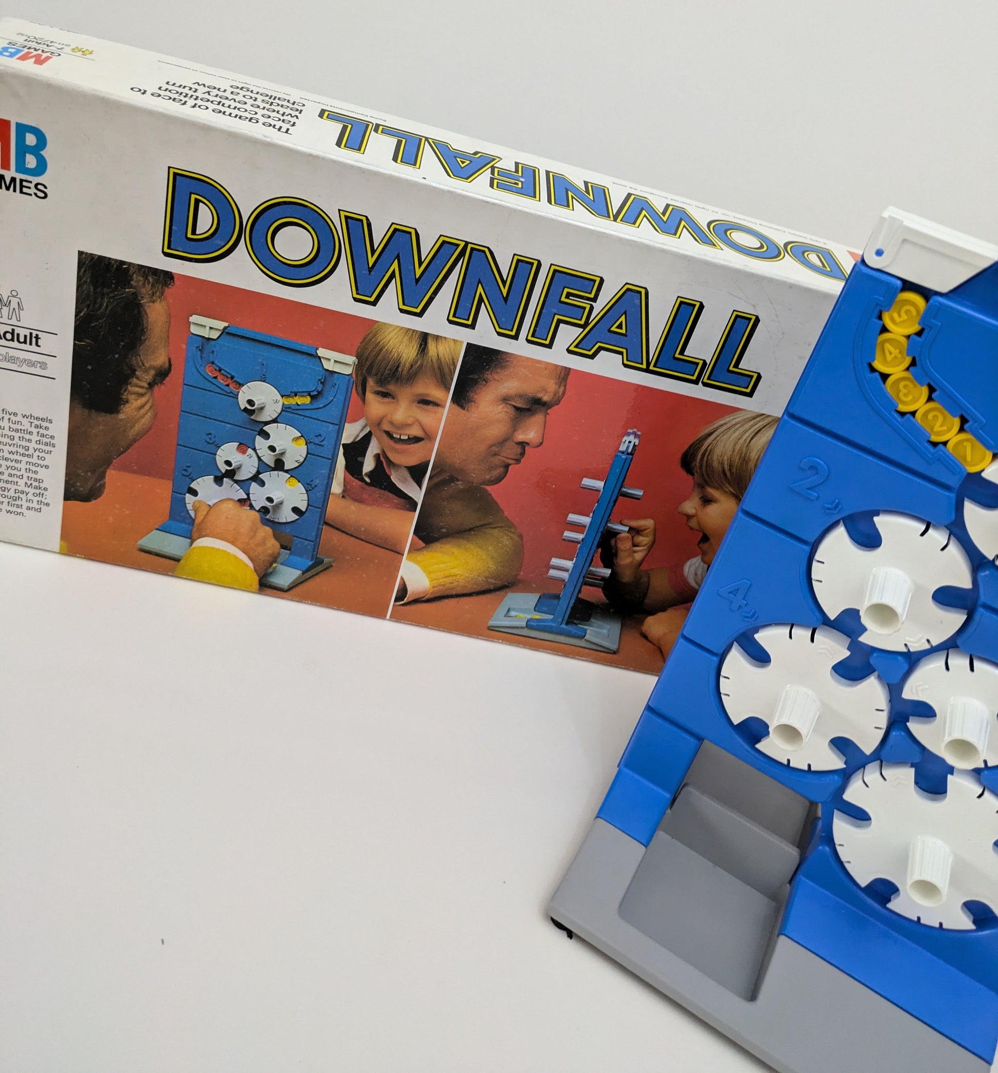 "Side view of Downfall game box showing colourful graphics of the dials, discs, and game logo, emphasizing its strategic gameplay."