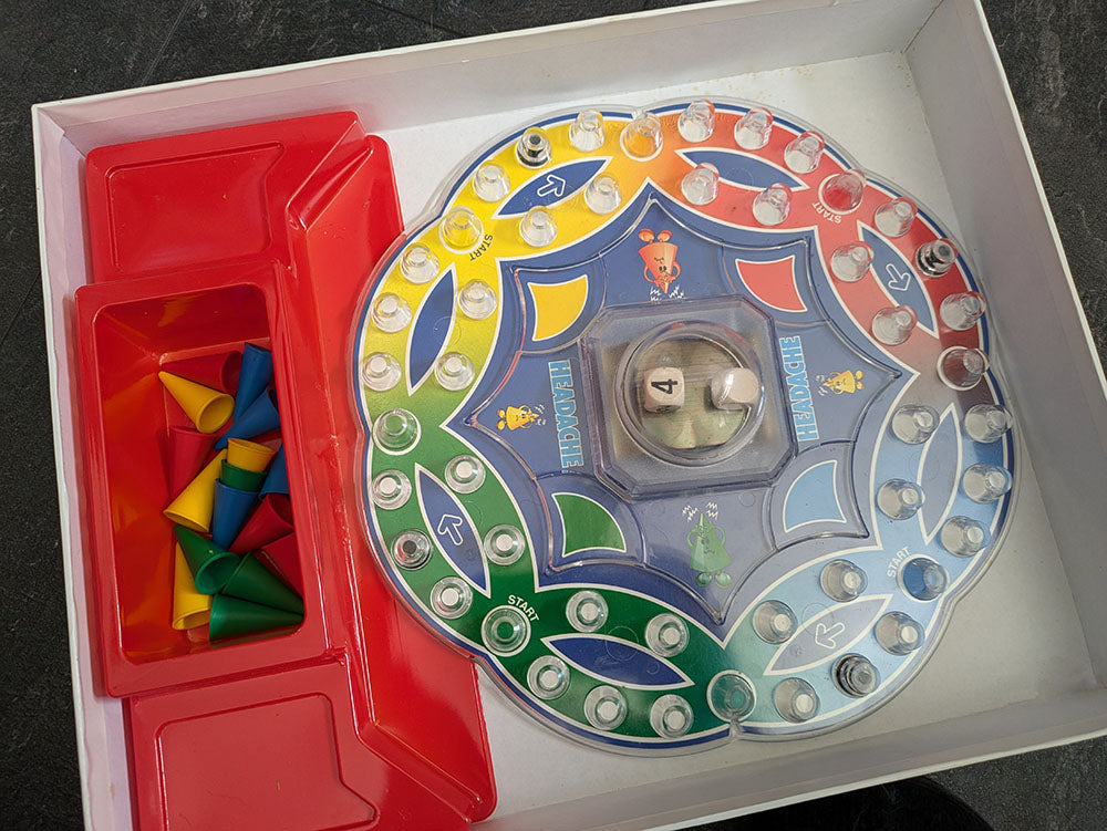 "Complete Headache game setup with game board, colourful cone pieces, and player tokens ready for strategic cone-stacking competition."