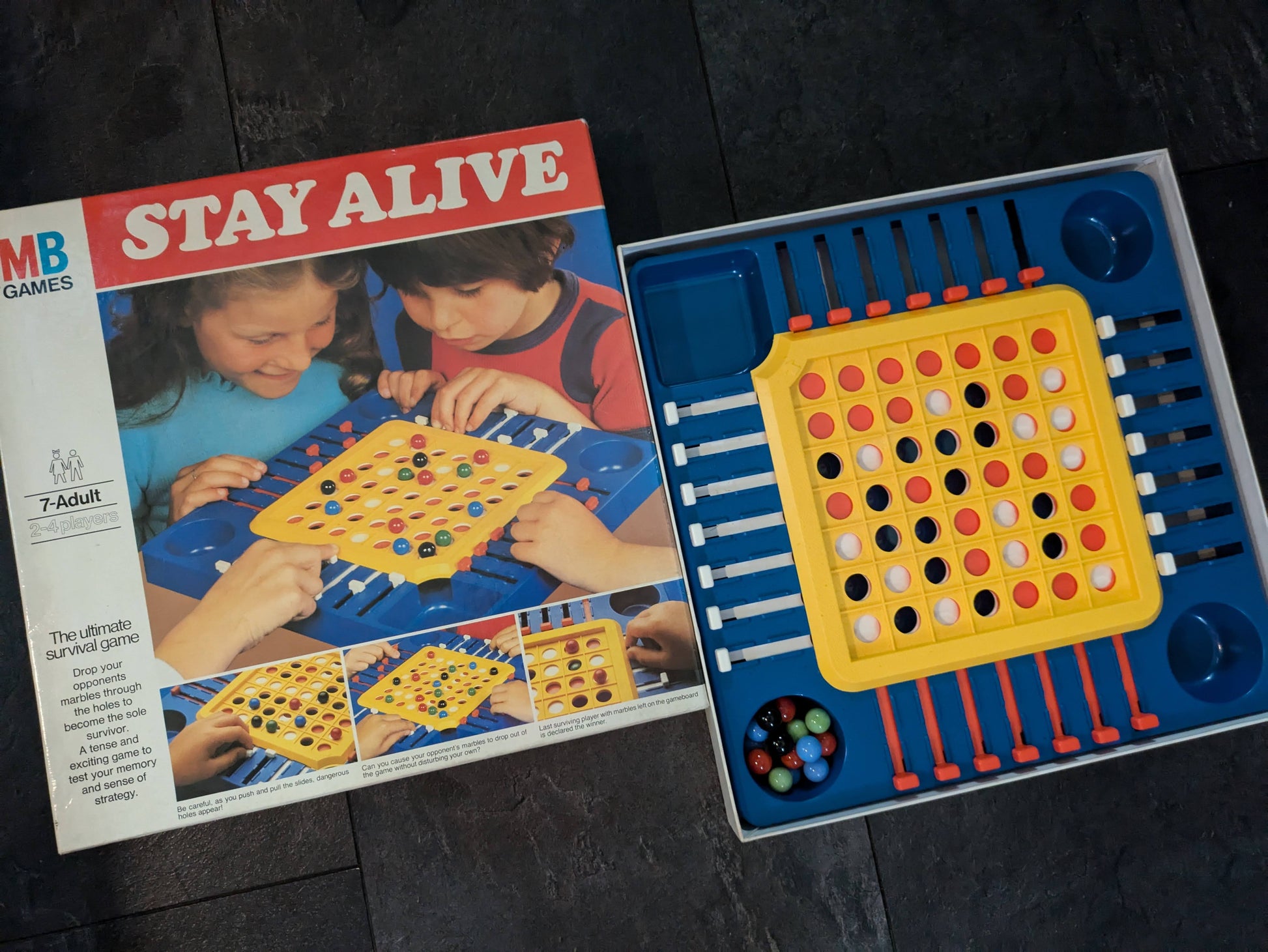 "Stay Alive (1975) game box featuring the marble survival board and sliding dials, emphasizing strategic and competitive gameplay."