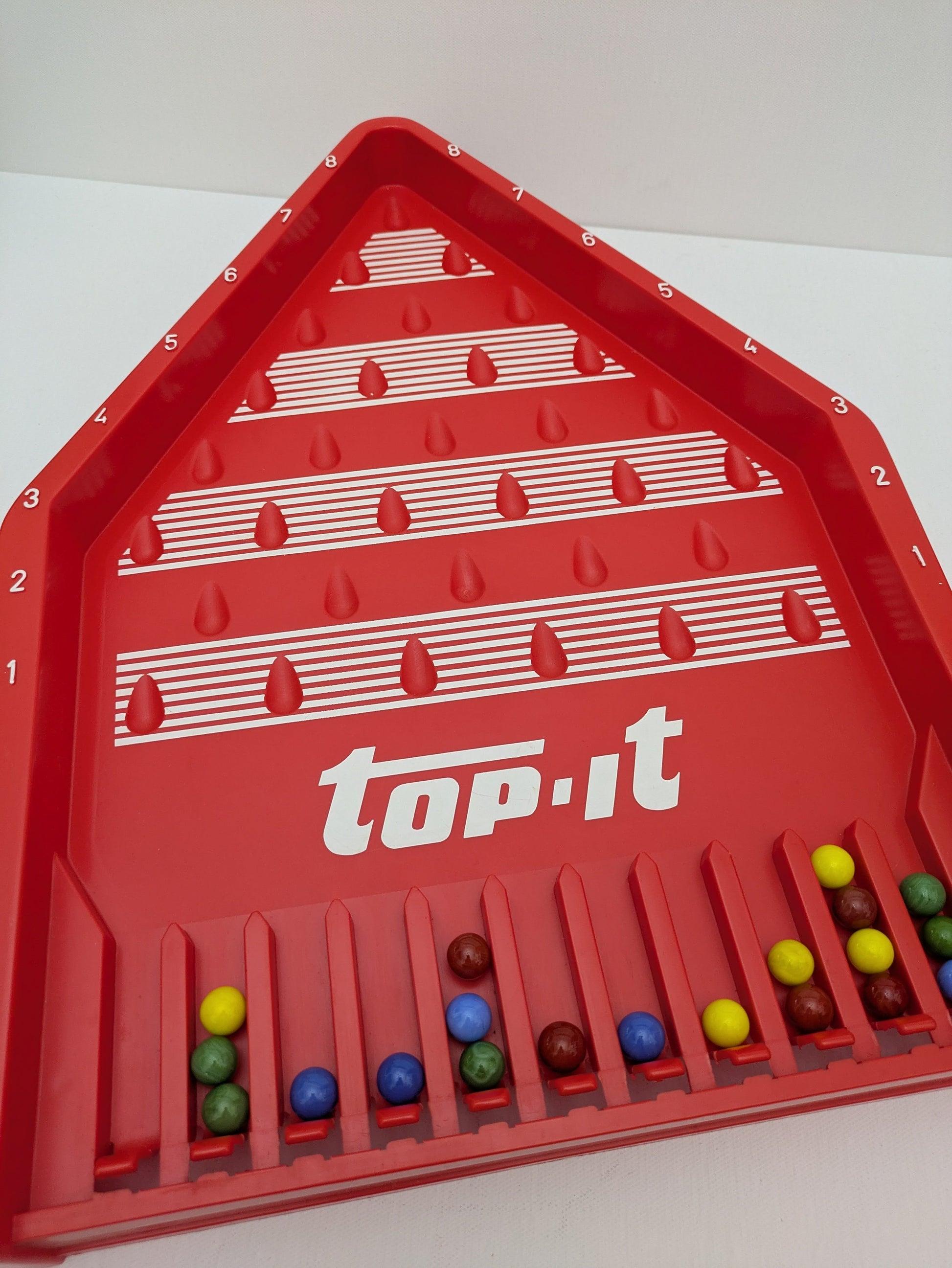Top-It (1972) is a vintage tabletop game that turns simple marble play into competitive family fun.