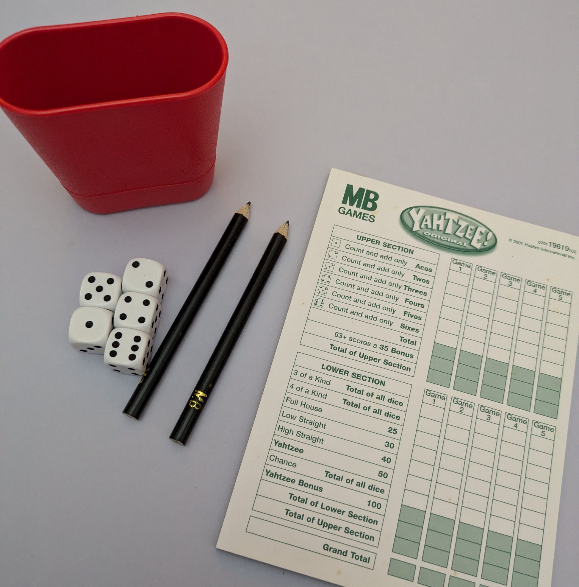 "Complete Yahtzee game setup with dice, scorecards, and a dice cup ready for exciting dice-rolling action."